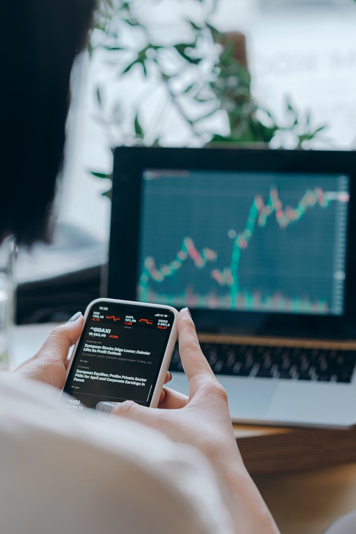 gallery-6 Person using smartphone for stock market analysis at home office.